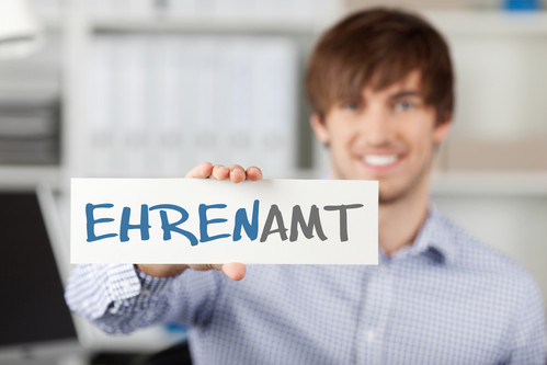 Symbolbild: Mann hält Schild hoch mit Schriftzug "EHRENAMT"