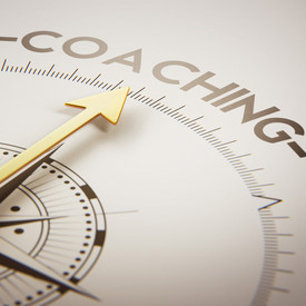 Zu sehen ist ein Kompass. Die Nadel zeigt auf das Wort Coaching. 