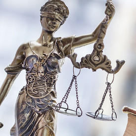 Prostituiertenschutzgesetz Figur der Justitia neben einem aufgeschlagen Buch- Symbolbild für Gesetzgebung