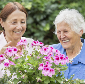 Seniorin steht vor Blumen 