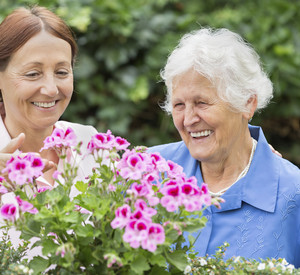 Seniorin steht vor Blumen