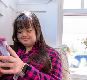 Eine Frau mit Down Syndrom benutzt ein Smartphone