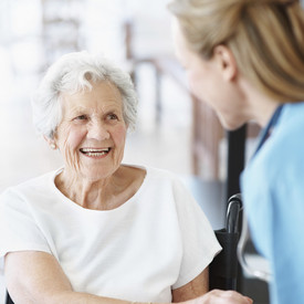 Pflegekraft hilft Seniorin aus dem Rollstuhl