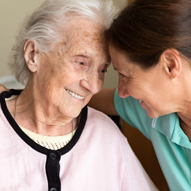 Junge Frau umarmt Seniorin