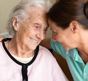 Junge Frau umarmt Seniorin