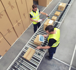 Zwei Arbeiter in einem Lager in der Logistikbranche, der Pakete am Fließband verarbeitet