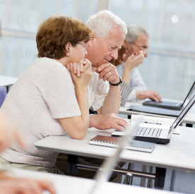 PC- und Internettreffs für ältere Menschen Ältere Menschen sitzen in einem Schulungsraum und haben Laptops vor sich stehen
